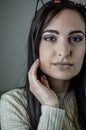 Portrait of a beautiful young woman with long brown hair with her hand on her cheek while she is staring Royalty Free Stock Photo