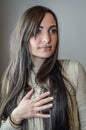 Portrait of a beautiful young woman with long brown hair with her hand on her chest looking intently to her left Royalty Free Stock Photo