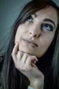 Portrait of a beautiful young woman with long brown hair looking up while thinking and touching her chin Royalty Free Stock Photo