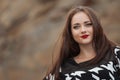 Portrait of the beautiful young woman with long brown hair pink flower posing at studio over dark background Royalty Free Stock Photo