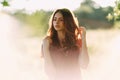 Portrait of beautiful young woman in with long brown hair in red pattern dress posing outdoors, dreaming, sensual, blurry smoky