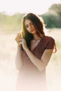 Portrait of beautiful young woman in with long brown hair in red pattern dress posing outdoors, dreaming, sensual, blurry smoky