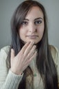 Portrait of a beautiful young woman with long brown hair touching her chin while looking intently Royalty Free Stock Photo