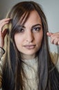 Portrait of a beautiful young woman with long brown hair who is arranging her hair Royalty Free Stock Photo