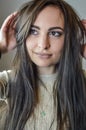 Portrait of a beautiful young woman with long brown hair who is smiling and arranging her hair Royalty Free Stock Photo