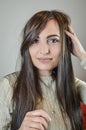 Portrait of a beautiful young woman with long brown hair who is smiling and arranging her hair Royalty Free Stock Photo