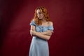 Portrait of a beautiful young woman with long curly red hair, dressed in a fashionable light light blue dress Royalty Free Stock Photo