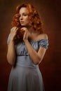 Portrait of a beautiful young woman with long curly red hair, dressed in a fashionable light light blue dress Royalty Free Stock Photo