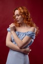 Portrait of a beautiful young woman with long curly red hair, dressed in a fashionable light light blue dress Royalty Free Stock Photo