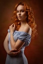 Portrait of a beautiful young woman with long curly red hair, dressed in a fashionable light light blue dress Royalty Free Stock Photo