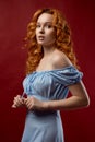 Portrait of a beautiful young woman with long curly red hair, dressed in a fashionable light light blue dress Royalty Free Stock Photo