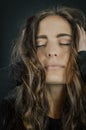 Portrait of a beautiful young woman with long hair with her hands in her hair with her eyes closed and an expression of intense pl Royalty Free Stock Photo