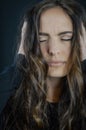 Portrait of a beautiful young woman with long hair with her hands in her hair with her eyes closed and an expression of pleasure Royalty Free Stock Photo