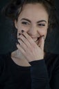 Portrait of a beautiful young woman with long hair laughing happily and covering her mouth with her hand Royalty Free Stock Photo