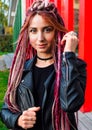 Portrait of a beautiful young woman with long pink dreadlocks and pigtails in black clothes. Model looks at the camera and smiles Royalty Free Stock Photo