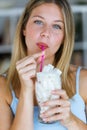 Beautiful young woman looking at camera while simulating to drink sugar in a glass cup at home.