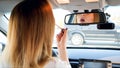 Portrait of beautiful young woman looking in car mirror while painting her lips with lipstick Royalty Free Stock Photo