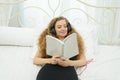 Portrait of a beautiful young woman lying on bed reading a book Royalty Free Stock Photo