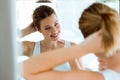 Beautiful young woman making hairstyle near mirror in the bathroom. Royalty Free Stock Photo