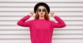 Portrait beautiful young woman model blowing her red lips wearing a pink knitted sweater and black round hat on a white Royalty Free Stock Photo