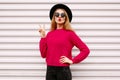 Portrait beautiful young woman model blowing her red lips wearing a pink knitted sweater and black round hat on a white Royalty Free Stock Photo