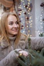 Portrait of beautiful young woman near the Christmas decorations standing outdoors. Christmas mood, holidays. Vertical frame Royalty Free Stock Photo