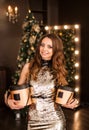 Portrait of a beautiful young woman with New Year`s gifts on the background of a Christmas tree Royalty Free Stock Photo
