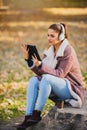 Portrait of beautiful young woman in the park using laptop computer listening over headphones studying outdoors in the nature Royalty Free Stock Photo