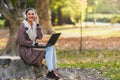 Portrait of beautiful young woman in the park using laptop computer listening over headphones studying outdoors in the nature Royalty Free Stock Photo