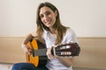 Portrait of a beautiful young woman playing guitar at home and h Royalty Free Stock Photo