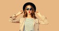 Portrait of beautiful young woman posing blowing her lips sends sweet air kiss wearing sunglasses, black round hat on beige studio Royalty Free Stock Photo