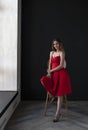 Portrait of a young woman in a red dress sitting on a high bar stool Royalty Free Stock Photo