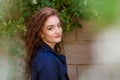 Beautiful young woman with red hair and freckles on background of wall Royalty Free Stock Photo