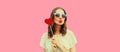 Portrait of beautiful young woman with red heart shaped lollipop blowing her lips with lipstick sending sweet air kiss wearing Royalty Free Stock Photo