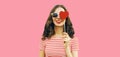 Portrait of beautiful young woman with red heart shaped lollipop wearing sunglasses on pink studio background Royalty Free Stock Photo