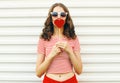 Portrait beautiful young woman with red heart shaped sunglasses blowing lips sending sweet air kiss on white wall Royalty Free Stock Photo