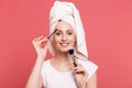 Portrait of beautiful young woman 20s wrapped in white towel after shower applying cosmetics with makeup brush Royalty Free Stock Photo