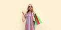 Portrait of beautiful young woman with shopping bags blowing her lips sends air kiss wearing summer colorful dress on white Royalty Free Stock Photo