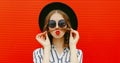 Portrait of beautiful young woman showing mustache her hair blowing red lips sending sweet air kiss wearing a black round hat Royalty Free Stock Photo