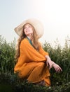 Portrait of beautiful young woman sitting in the grass. Hat and red dress Royalty Free Stock Photo