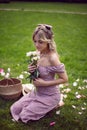 portrait of a beautiful young woman sitting on a green meadow in summer and holding a bouquet of pions. Royalty Free Stock Photo