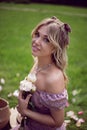 portrait of a beautiful young woman sitting on a green meadow in summer and holding a bouquet of pions. Royalty Free Stock Photo