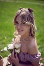 portrait of a beautiful young woman sitting on a green meadow in summer and holding a bouquet of pions. Royalty Free Stock Photo