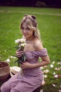 portrait of a beautiful young woman sitting on a green meadow in summer and holding a bouquet of pions. Royalty Free Stock Photo