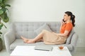Portrait of beautiful young woman sitting on sofa at home with laptop and talk on the phone with friends Royalty Free Stock Photo