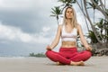 Portrait of a beautiful young woman sitting in yoga pose at the beach Royalty Free Stock Photo