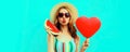 Portrait of beautiful young woman with slice of fresh watermelon and big red heart shaped balloon blowing her lips wearing summer Royalty Free Stock Photo