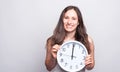 Portrait of beautiful young woman smiling and holding big white clock at twelve a clock Royalty Free Stock Photo
