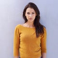 Her confidence is alluring. Portrait of a beautiful young woman standing confidently against a grey wall.