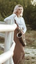 Portrait of a beautiful young woman standing and leaninf on wooden white fence with saxophone, romantic blonde girl relaxing on Royalty Free Stock Photo